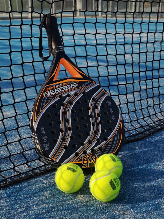 pexels-photo-4536850 From above of padel racket and small colorful balls near fence on sports ground